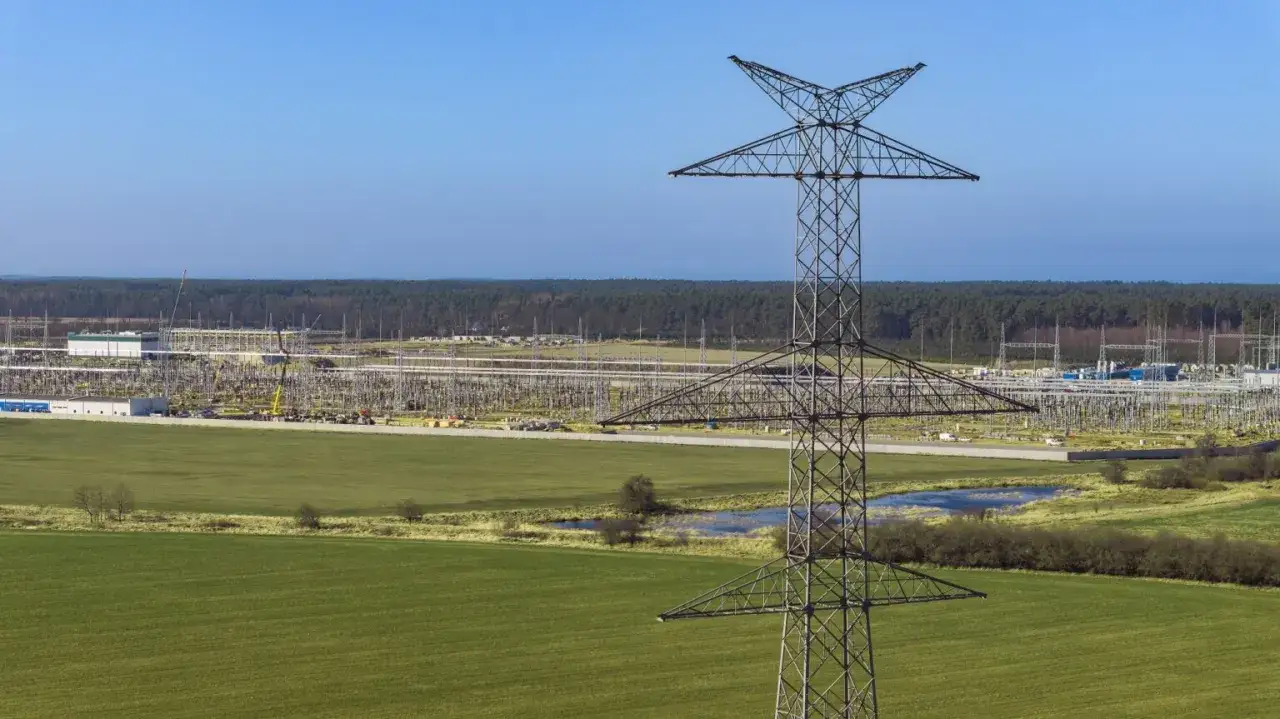 Wielka wieża energetyczna góruje nad krajobrazem, gdzie rozciąga się rozległa infrastruktura do transportu przesyłowego.