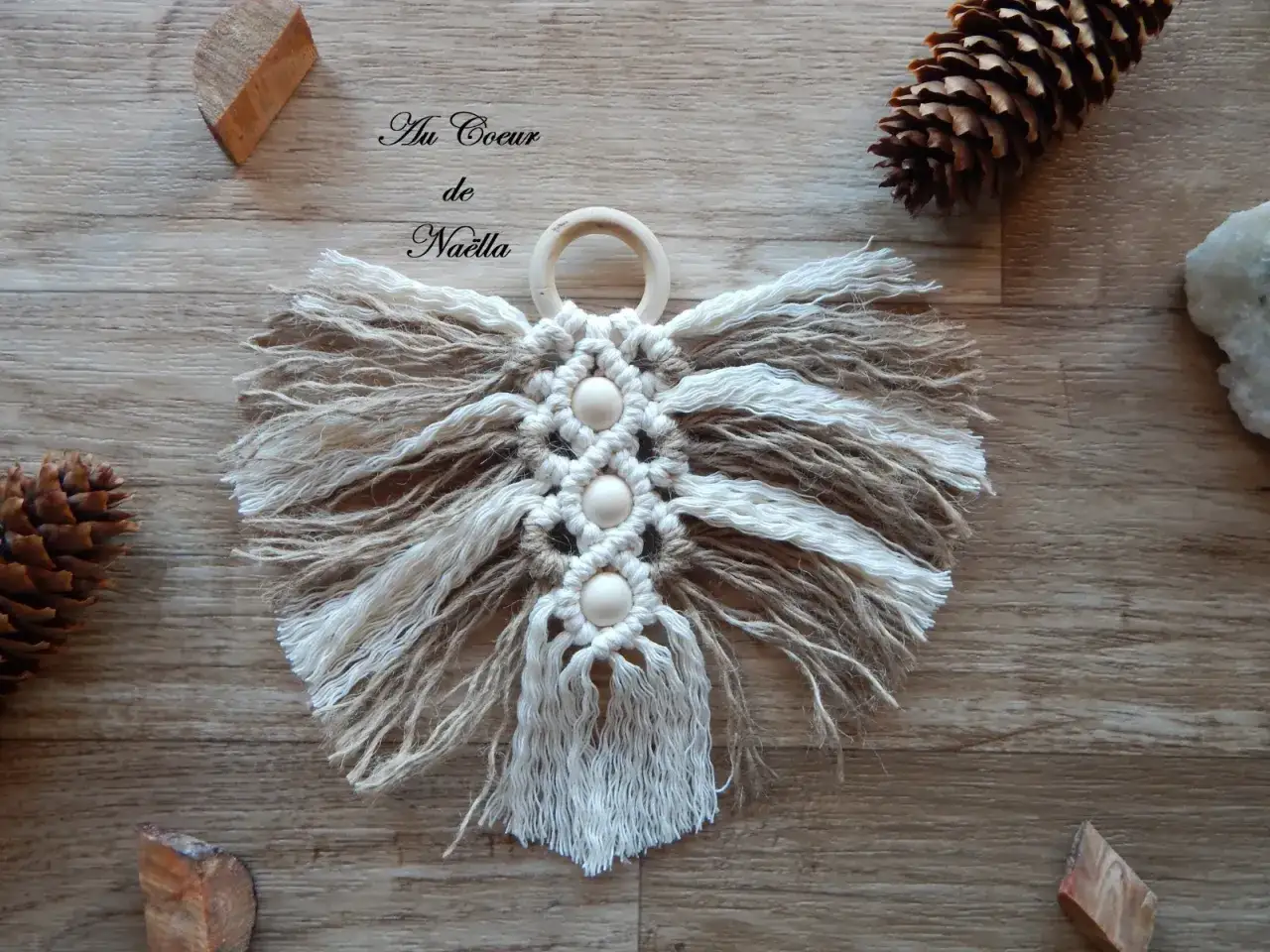 Décoration murale en macramé, forme d'ange aux ailes ébouriffées, avec perles en bois et un anneau.