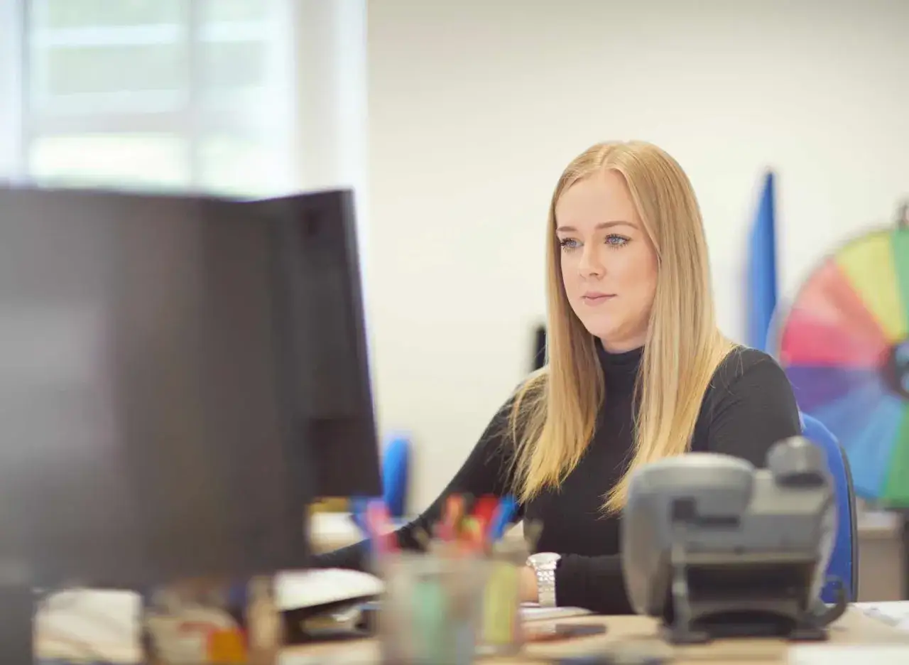 Mujer rubia trabajando en su ordenador, un ejemplo de microempresa definici&oacute;n en acci&oacute;n.
