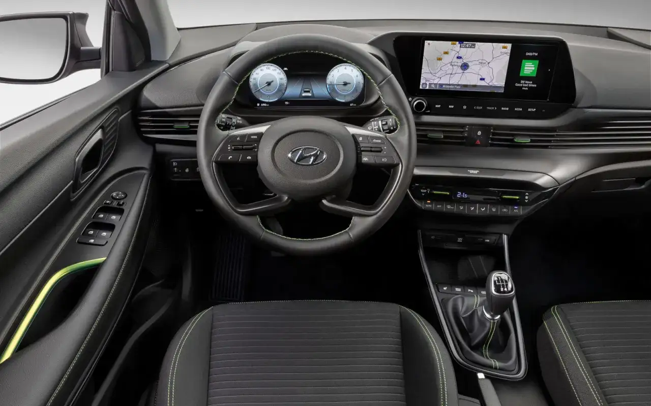 Wnętrze Hyundai i20: nowoczesny kokpit z ekranem nawigacji i cyfrowymi zegarami. Wiele osób chwali sobie te **hyundai i20 opinie**.