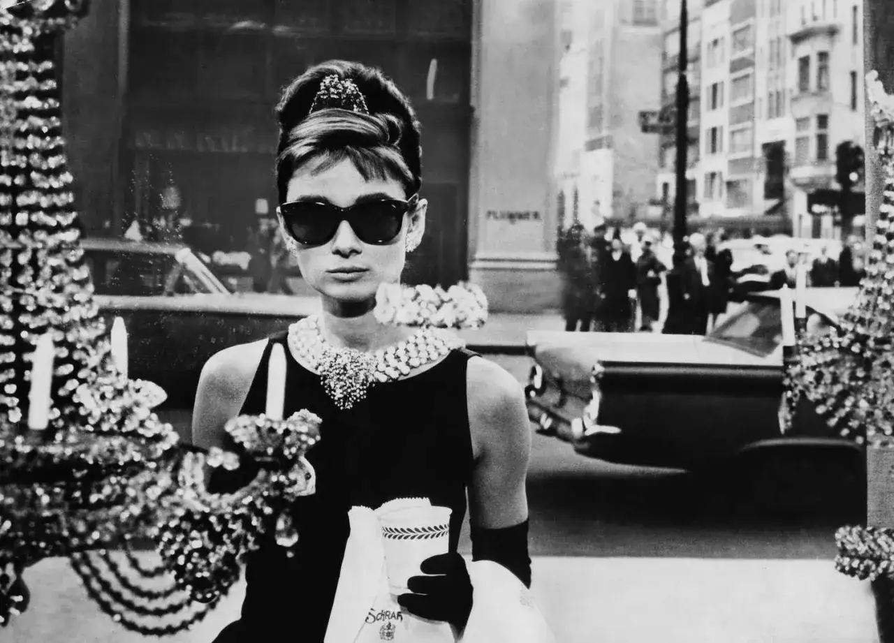 Audrey Hepburn w ikonicznej roli, z kawą w ręku, jakby śpiewała 
