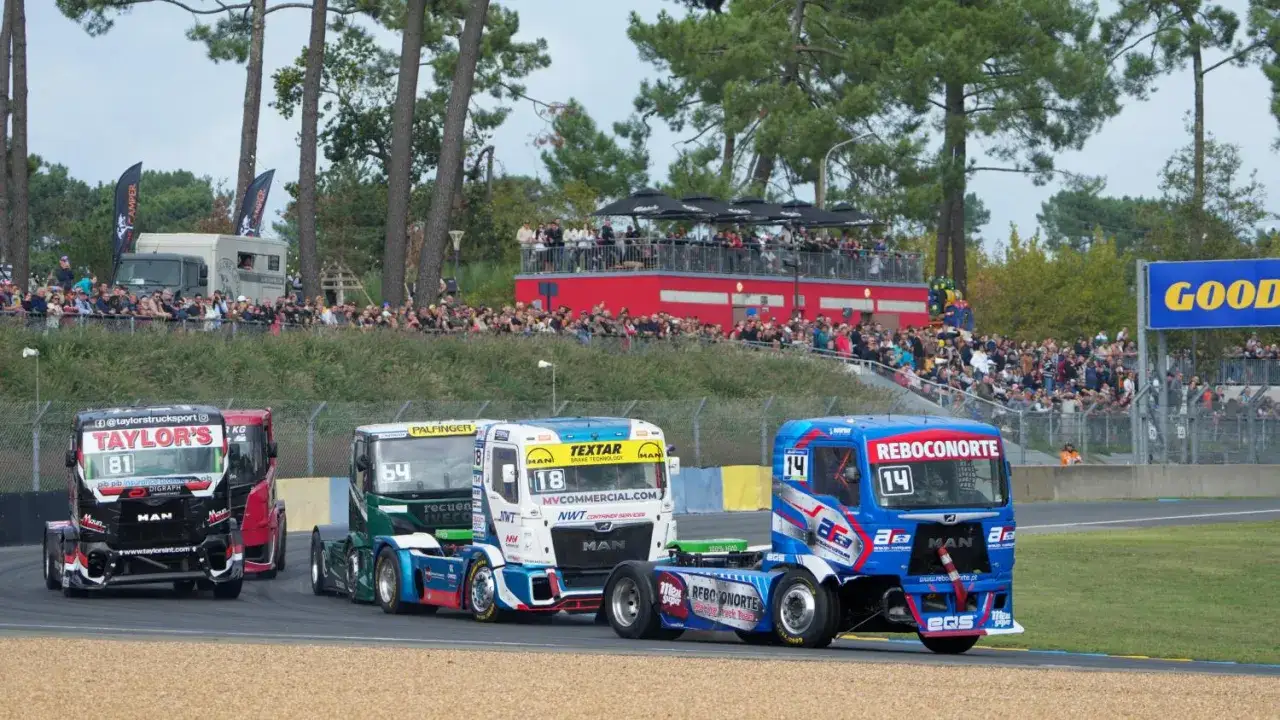 Trois camions de course s'affrontent lors d'un grand prix camion, sous les regards d'une foule en délire.