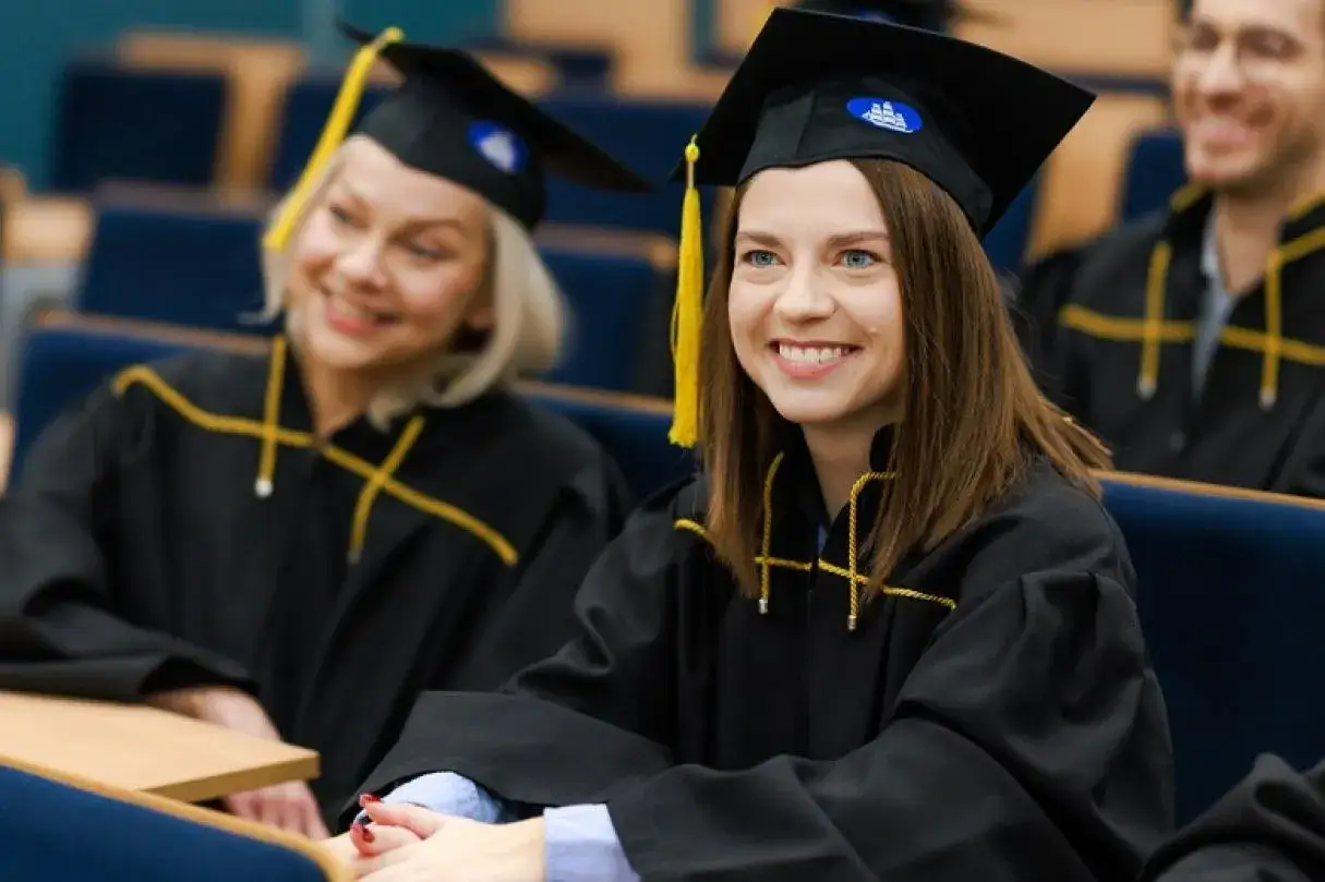 Uśmiechnięci absolwenci w togach na Akademii Leona Koźmińskiego. Czesne za studia to inwestycja w przyszłość.