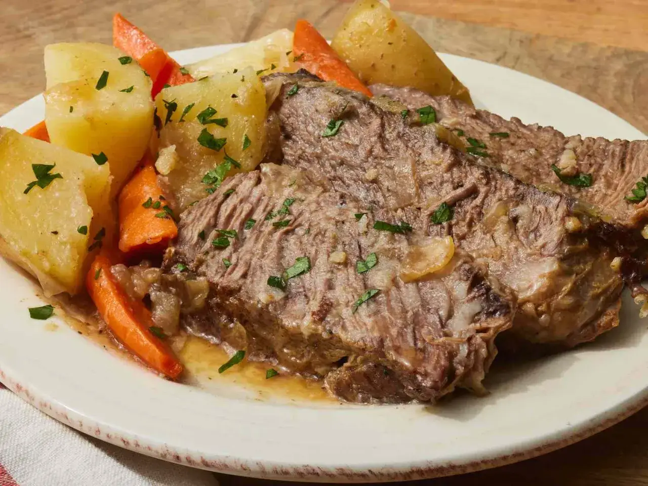 Saftiges, **schnelles Fleisch aus dem Ofen** mit Kartoffeln und Karotten, garniert mit Petersilie.