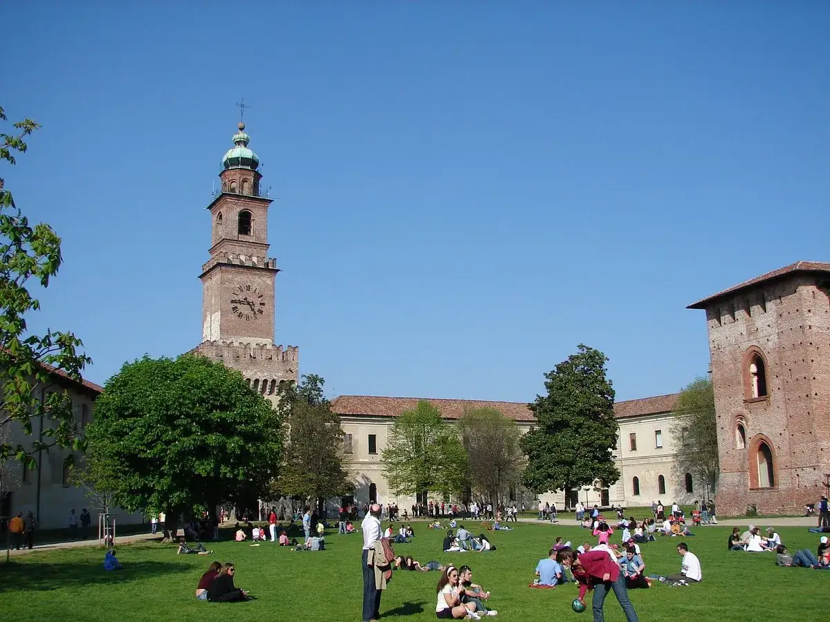 Piazza con torre dell'orologio e gente sull'erba: ecco cosa vedere a Vigevano in un giorno.