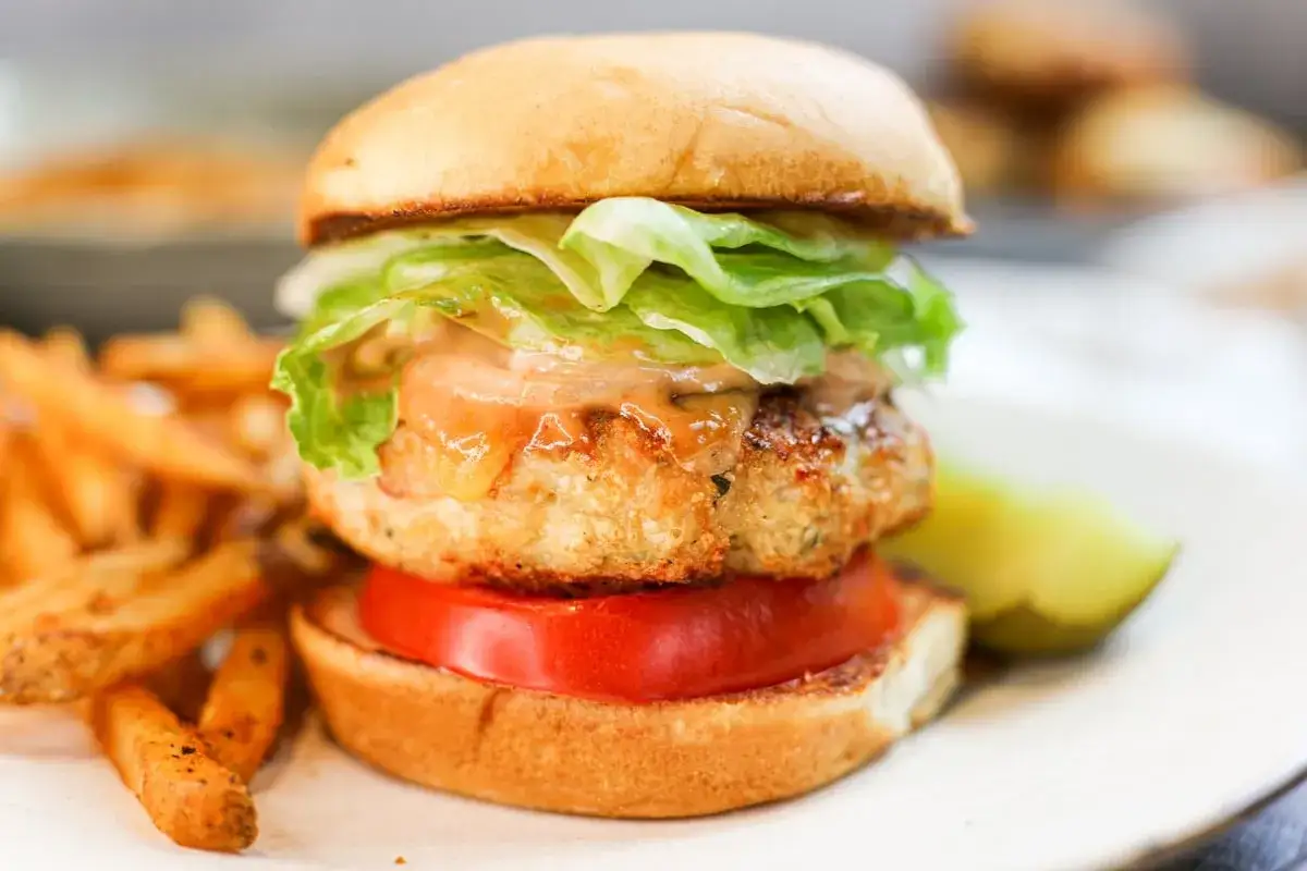 Deliciosa hamburguesa de pollo con lechuga fresca, tomate y salsa especial, acompañada de papas fritas crujientes.