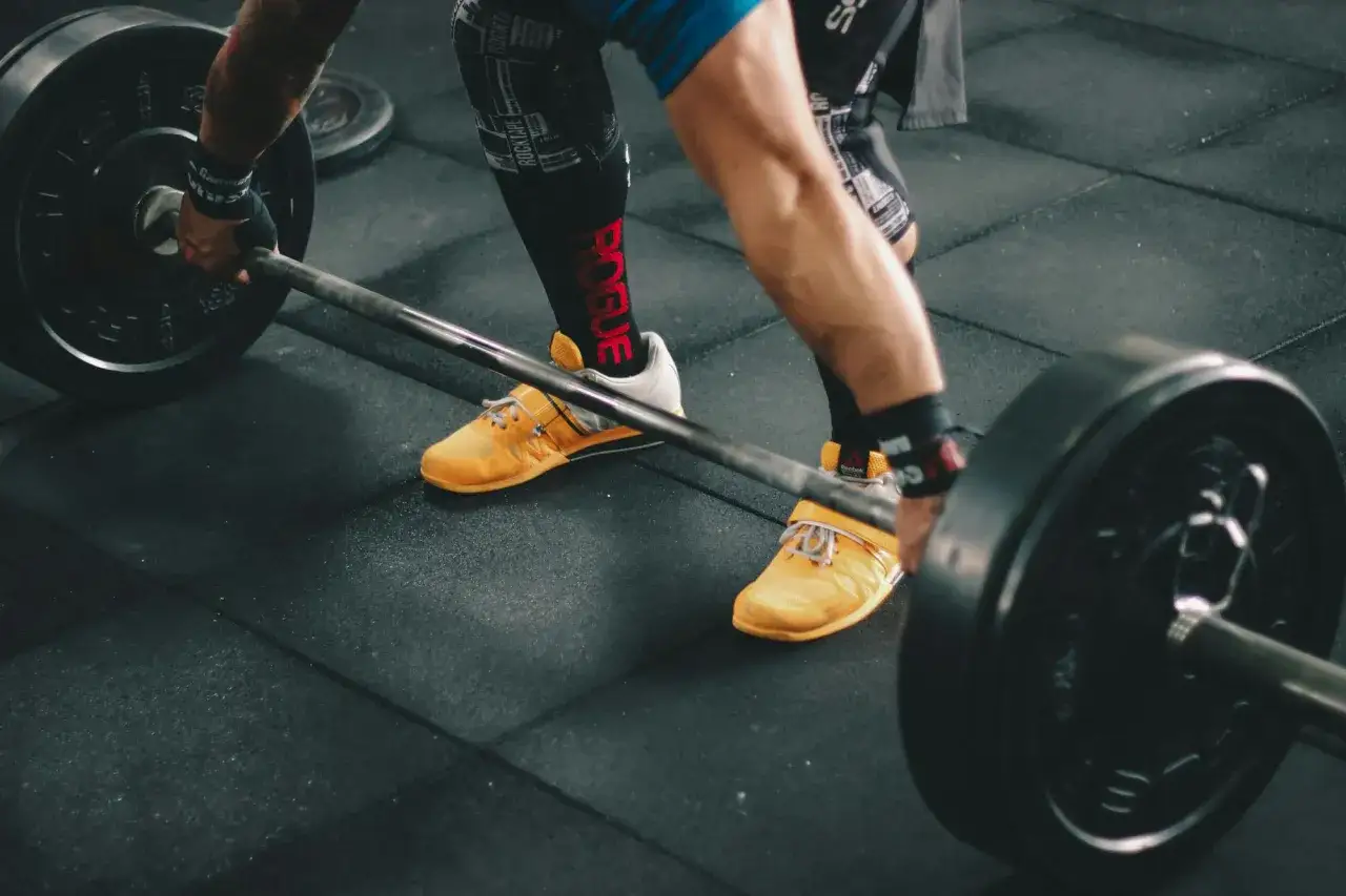 Przygotowanie do podnoszenia ciężarów. Czy to crossfit czy siłownia, żółte buty i opaski na nadgarstki sugerują intensywny trening.