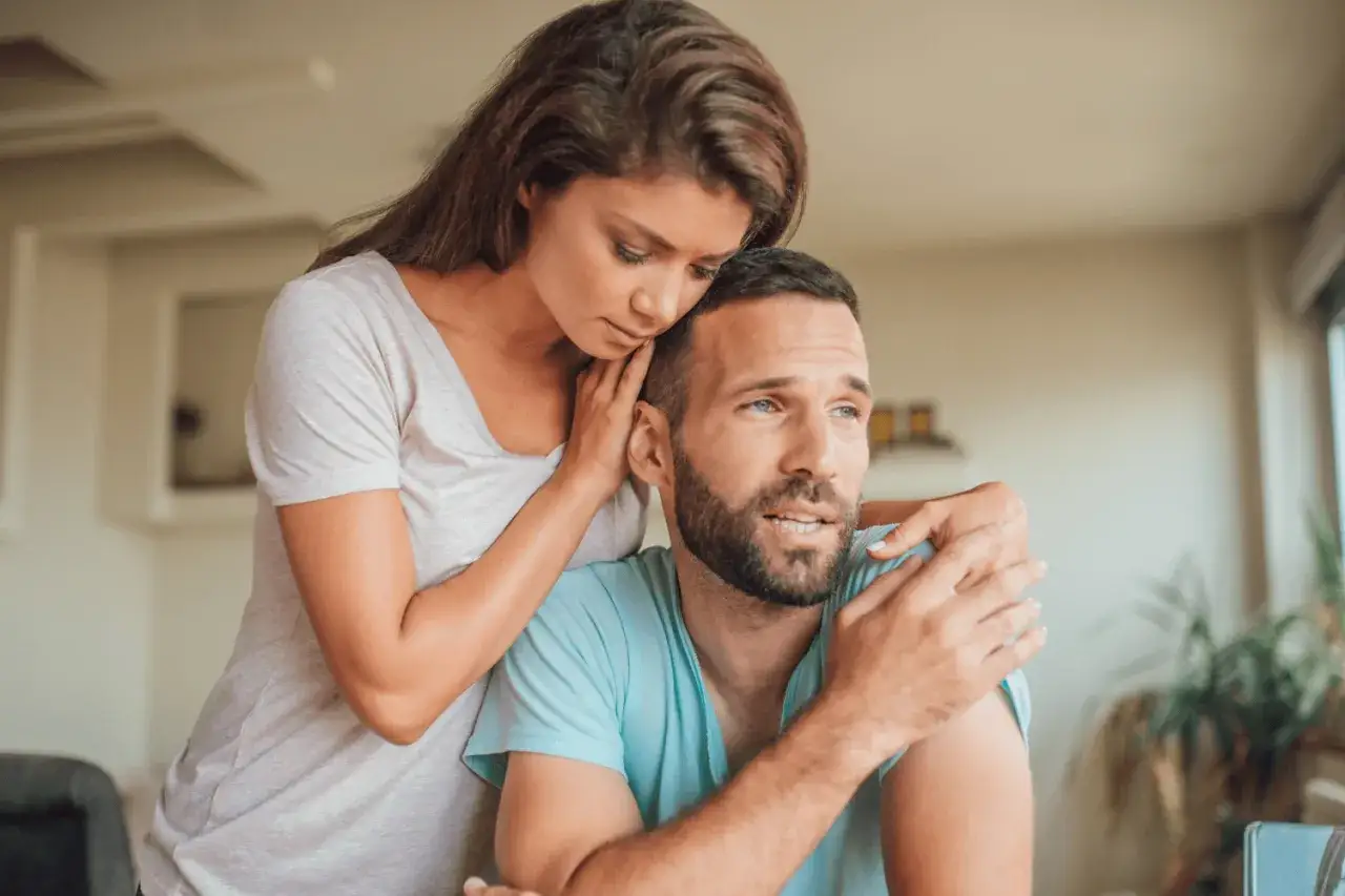 Une femme réconforte son conjoint, le bras autour de son épaule. Elle semble préoccupée, peut-être se demande-t-elle que faire quand on a des doutes sur son conjoint.