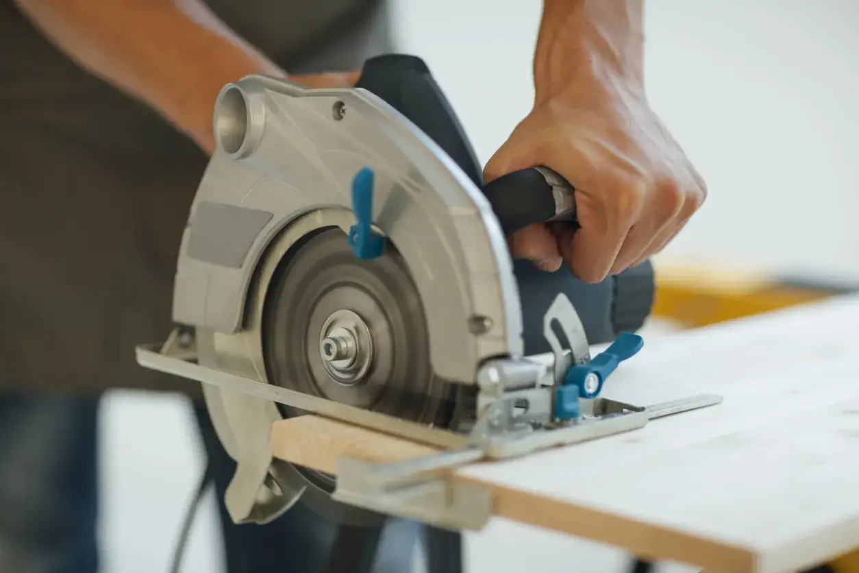 Main tenant une scie circulaire pour couper du bois. Apprenez comment utiliser une scie circulaire pour vos projets de bricolage.