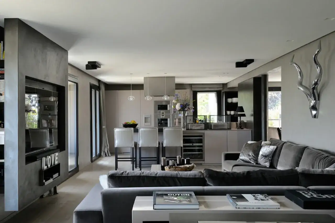 Interni open space di case moderne: un salotto accogliente con divano in velluto e cucina a vista con isola.