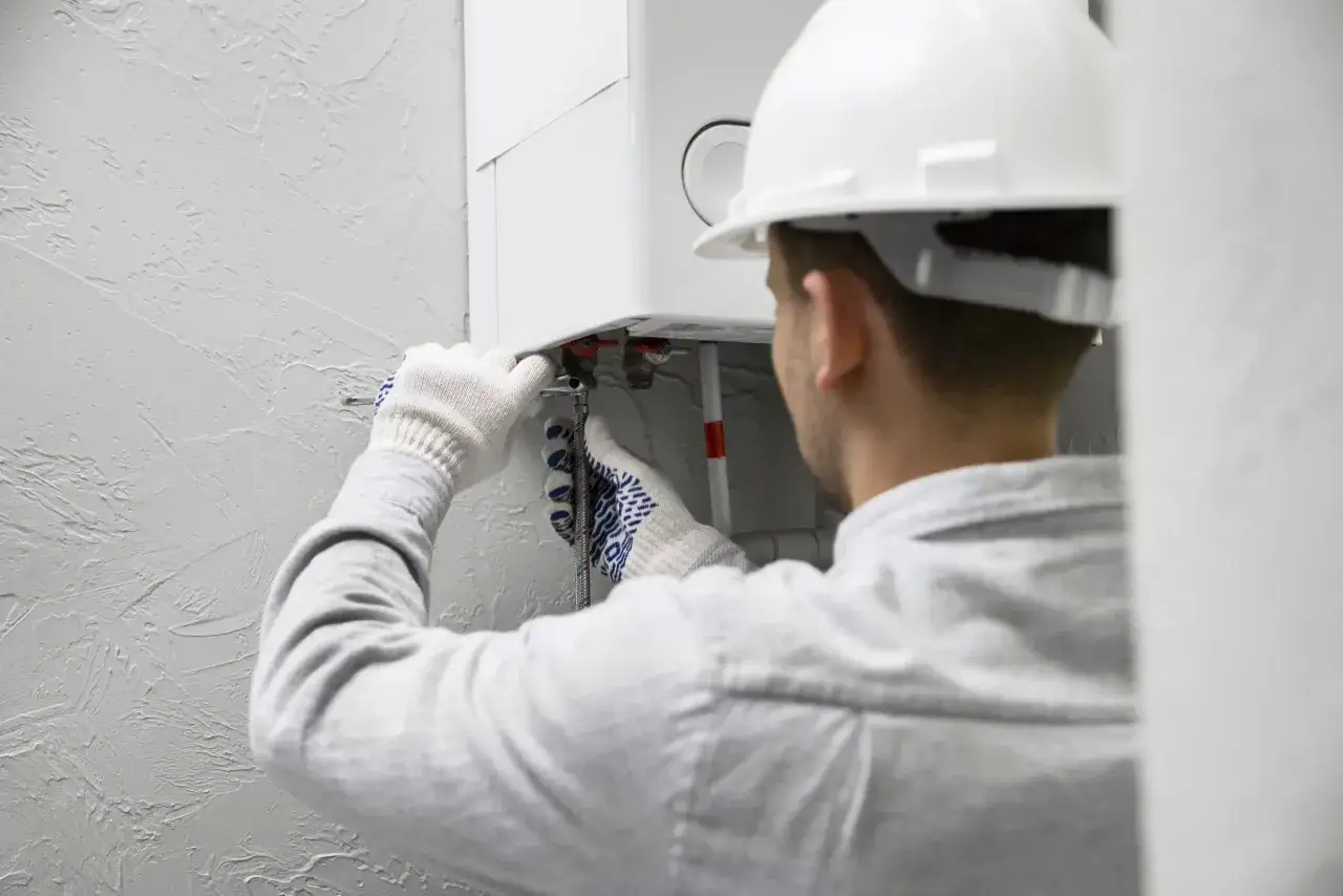 Tecnico con casco bianco lavora su una caldaia. Speriamo che non faccia rumore di notte!
