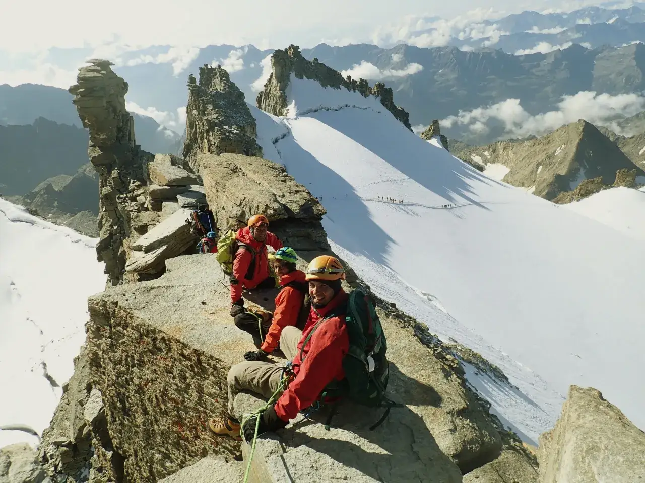 Groupe de randonneurs sur un sentier rocheux, profitant d'une vue spectaculaire sur les sommets des Alpes. Un sommet 4000 alpes facile à atteindre.