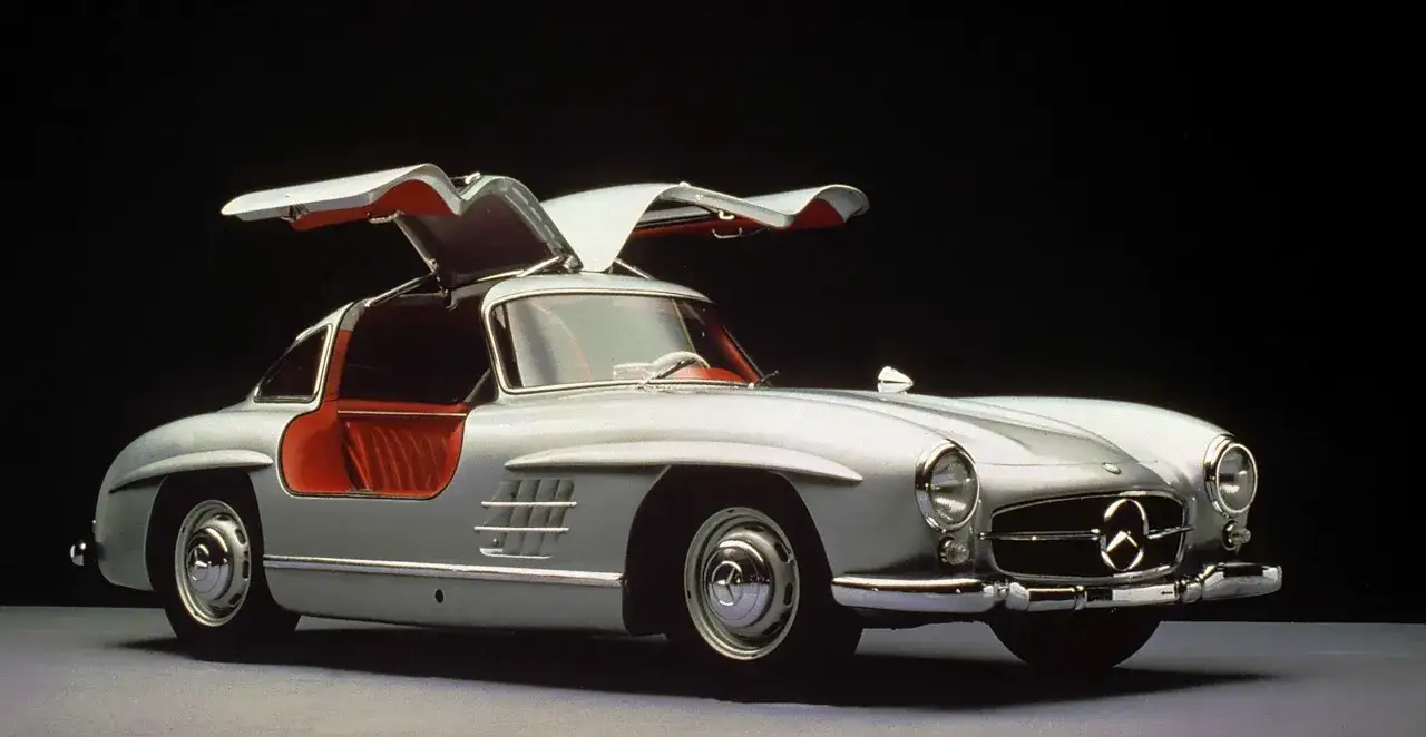 Srebrny Mercedes 300 SL Gullwing z otwartymi drzwiami, czerwonym wnętrzem. To najładniejsze auto na świecie, ikona motoryzacji.
