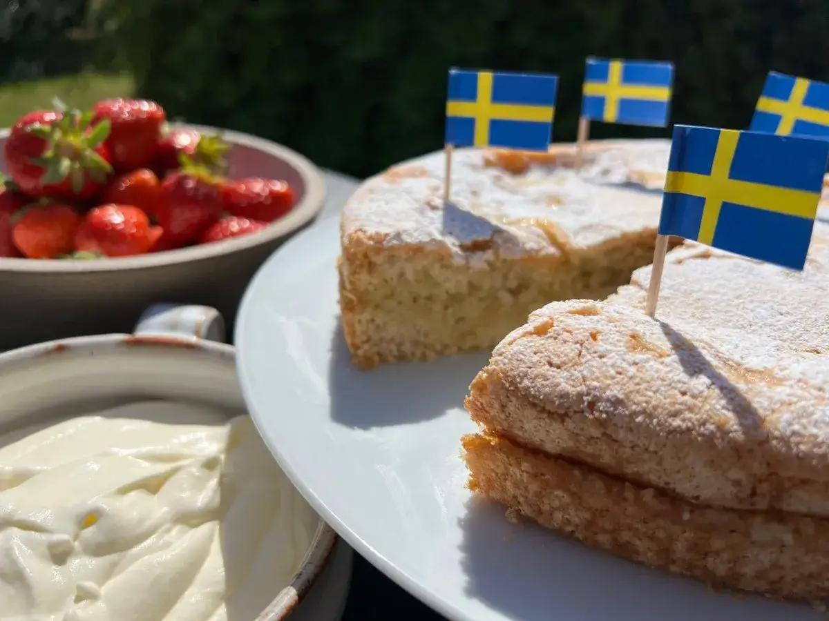 En h&auml;rlig glutenfri sverigekaka med svenska flaggor, serverad med jordgubbar och gr&auml;dde. Perfekt f&ouml;r nationaldagen!