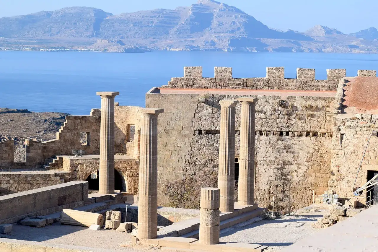 Starożytne ruiny Akropolu w Lindos, Rodos. Majestatyczne kolumny i kamienne mury świadczą o bogatej historii, a błękitne morze w tle dopełnia obraz najpiękniejszych miejsc na Rodos.