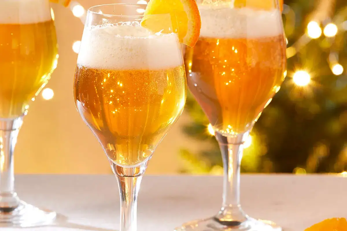 Trois verres de bière dorée, ornés d'une tranche d'orange, scintillent sous les lumières festives. Une boisson qui, malgré son allure festive, peut être mauvaise pour la santé.