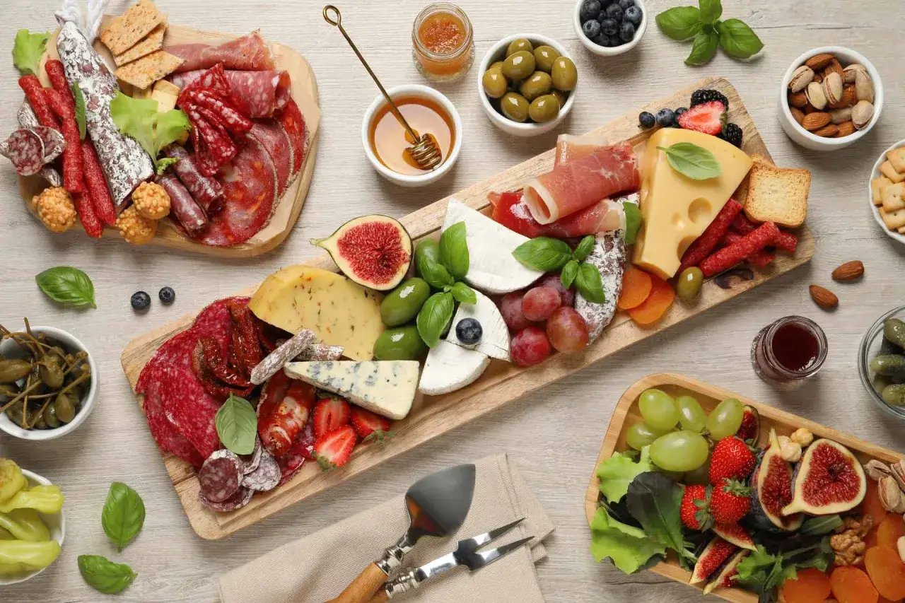 Un ricco tagliere di antipasti con salumi, formaggi, frutta fresca, olive e crostini, perfetto per un aperitivo conviviale.