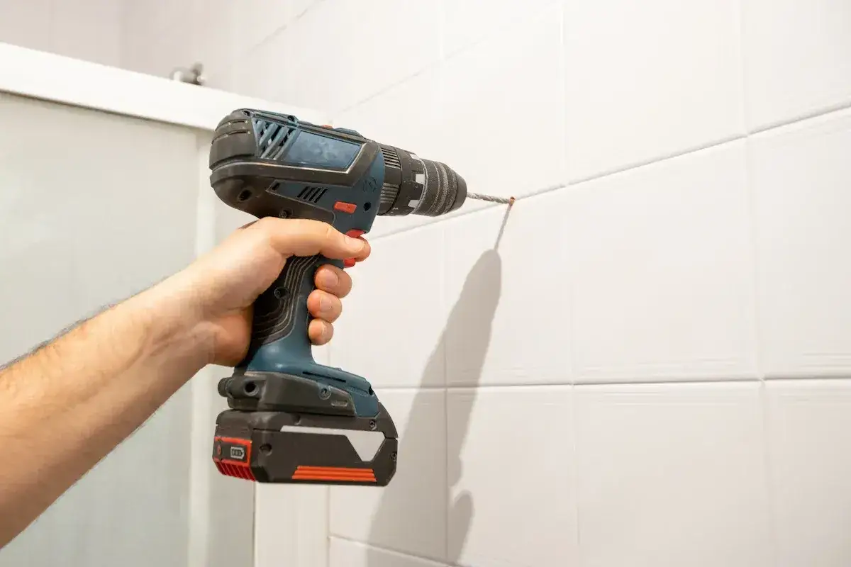 Mano che usa un trapano per fare un foro nella ceramica, mostrando come forare la ceramica senza romperla.
