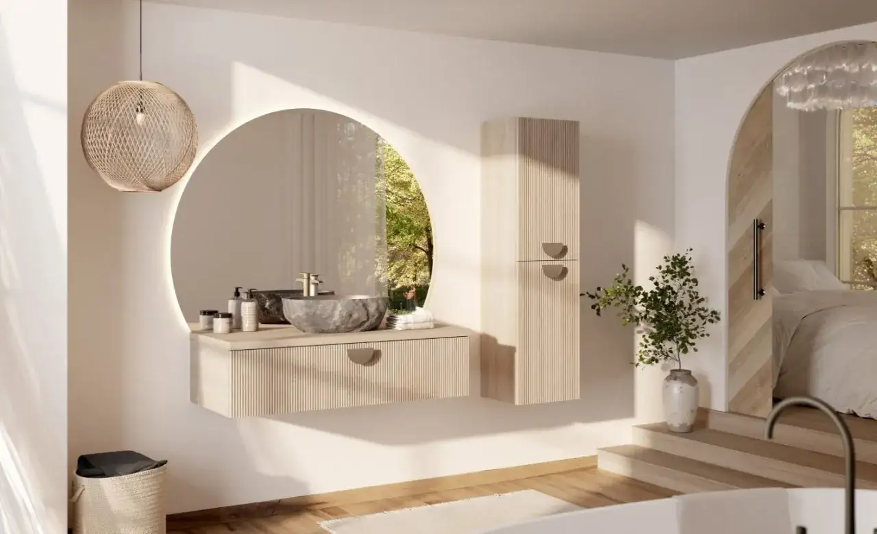 Salle de bain petite aux tons clairs. Meuble vasque suspendu, miroir rond lumineux, colonne de rangement en bois clair.