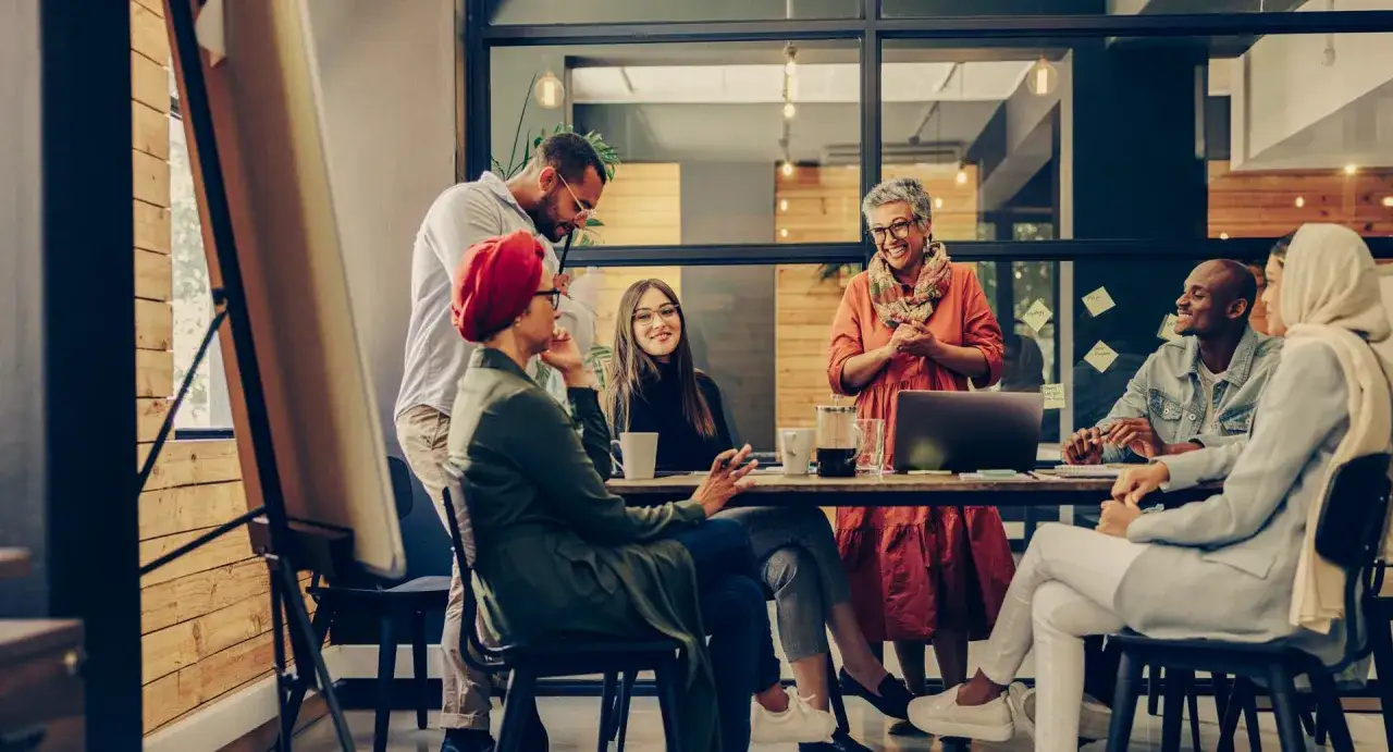 A diverse team collaborates, building their professional reputation through open discussion and shared ideas in a modern office setting.