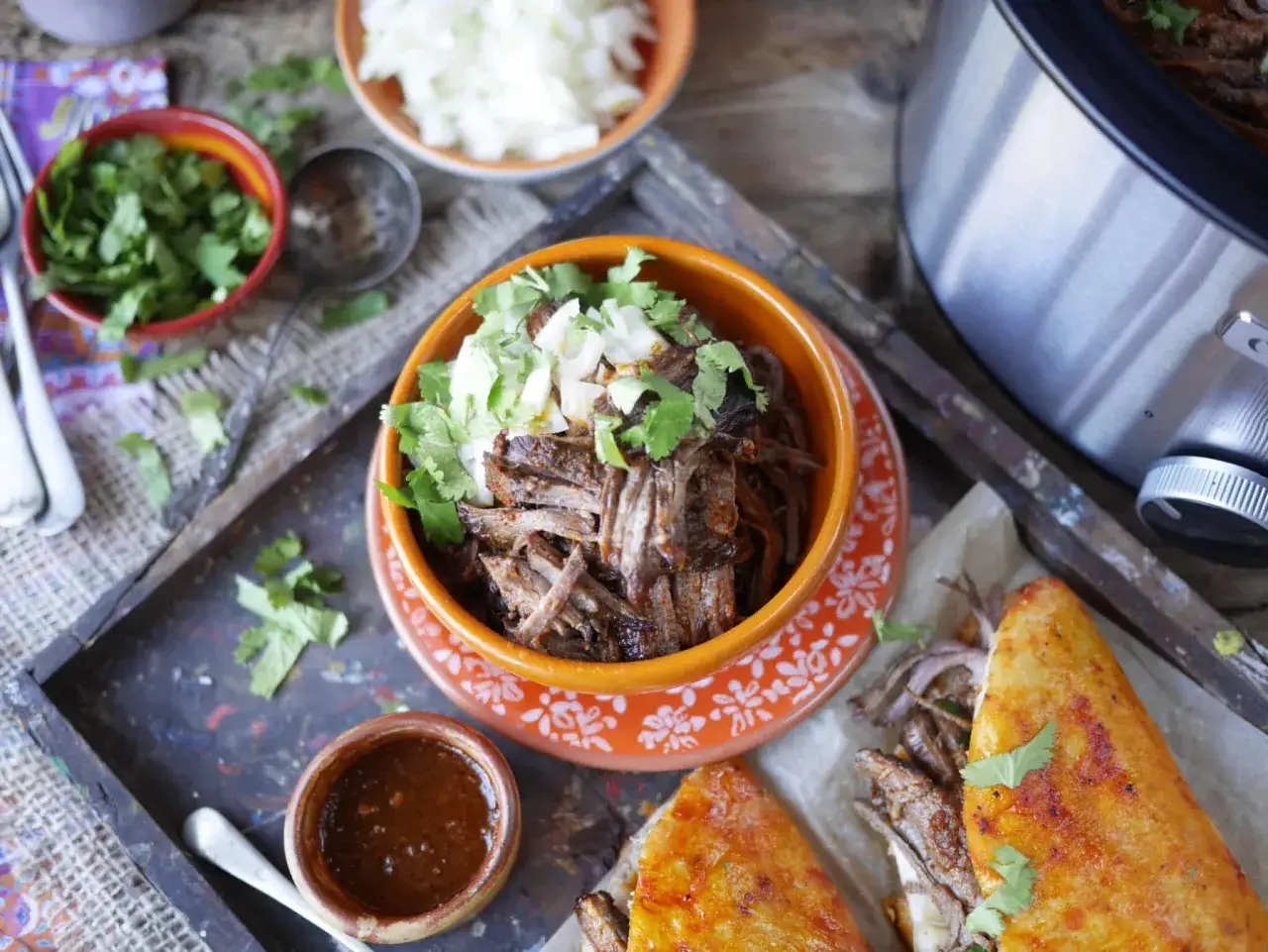 Saftig el birria, toppad med lök och koriander, serveras med en kryddig sås och gyllene quesadillas.