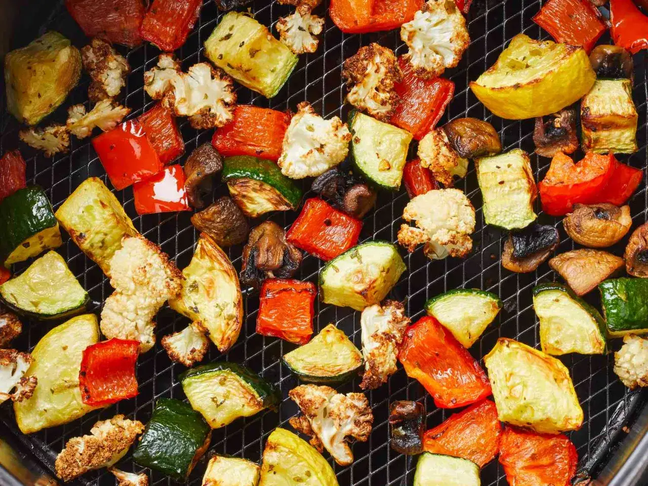 Verdure in friggitrice ad aria: zucchine, peperoni rossi, cavolfiore e funghi, cotti alla perfezione su una griglia.