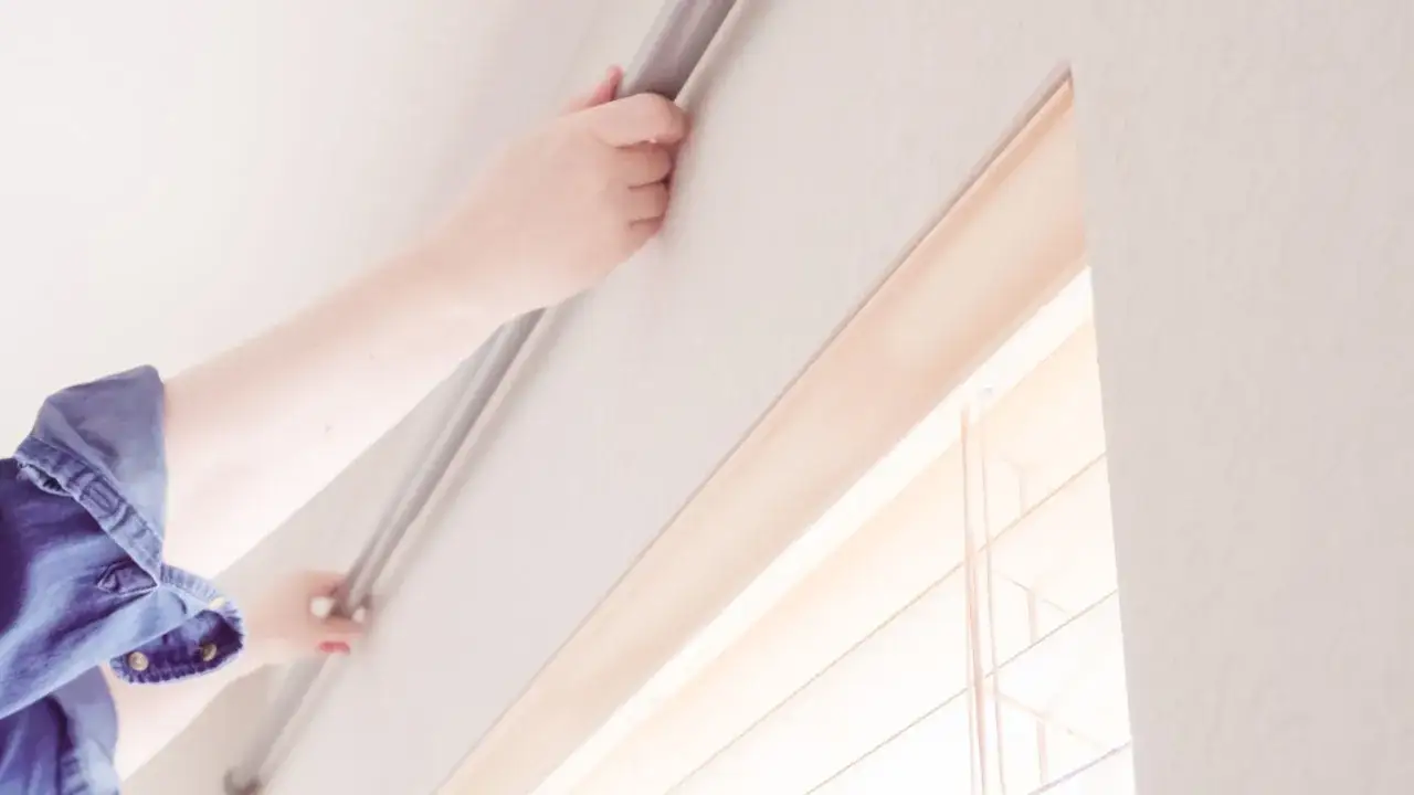 H&auml;nde bringen eine Gardinenstange an der Wand an, um einen Vorhang anzubringen.