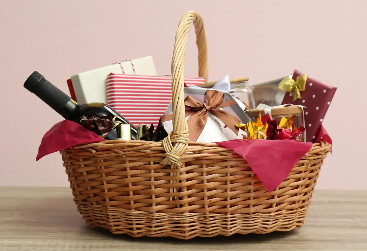 A wicker basket filled with gifts, including a bottle of wine, chocolates, and wrapped presents, perfect for raffle ideas.