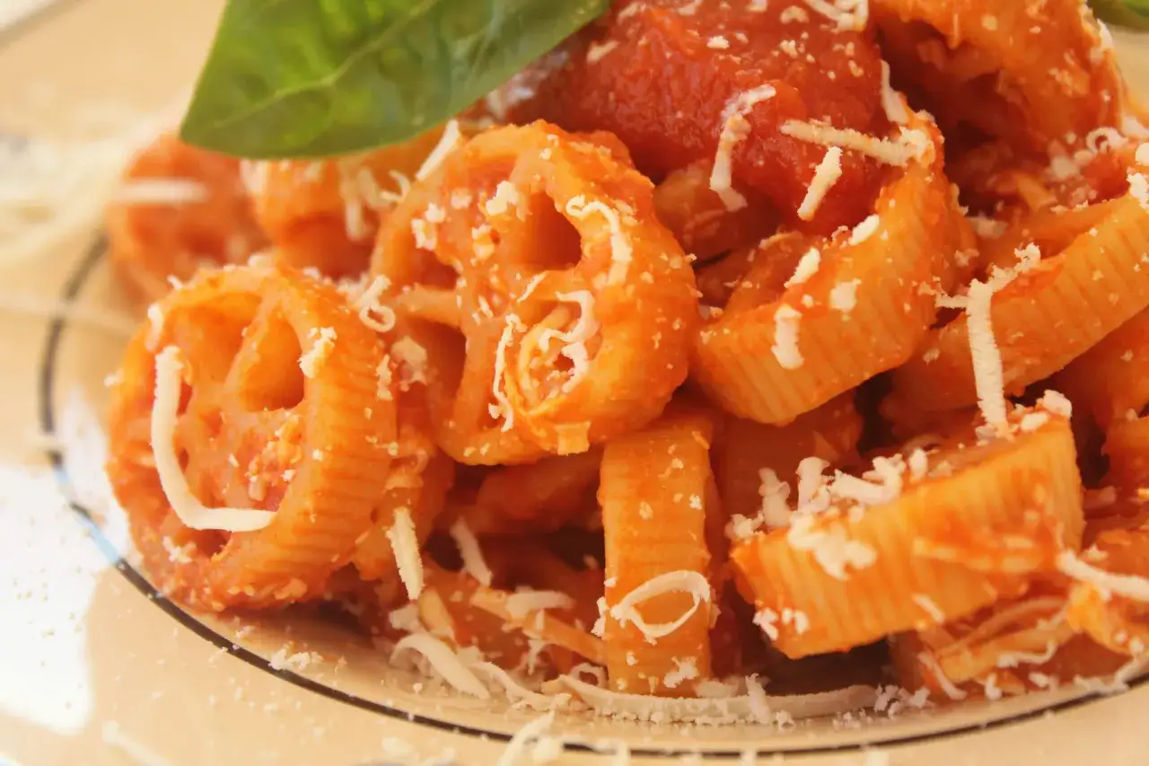 Pasta con ruote e rigatoni conditi con una ricca salsa di pomodoro Bimby, spolverata di parmigiano e guarnita con una foglia di basilico fresco.