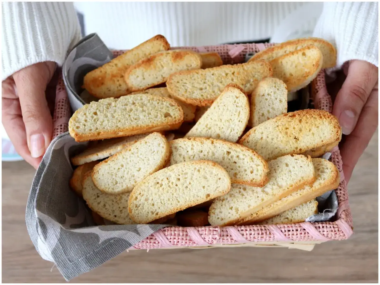 Un cestino rosa pieno di biscotti veneziani dorati, pronti per essere gustati.