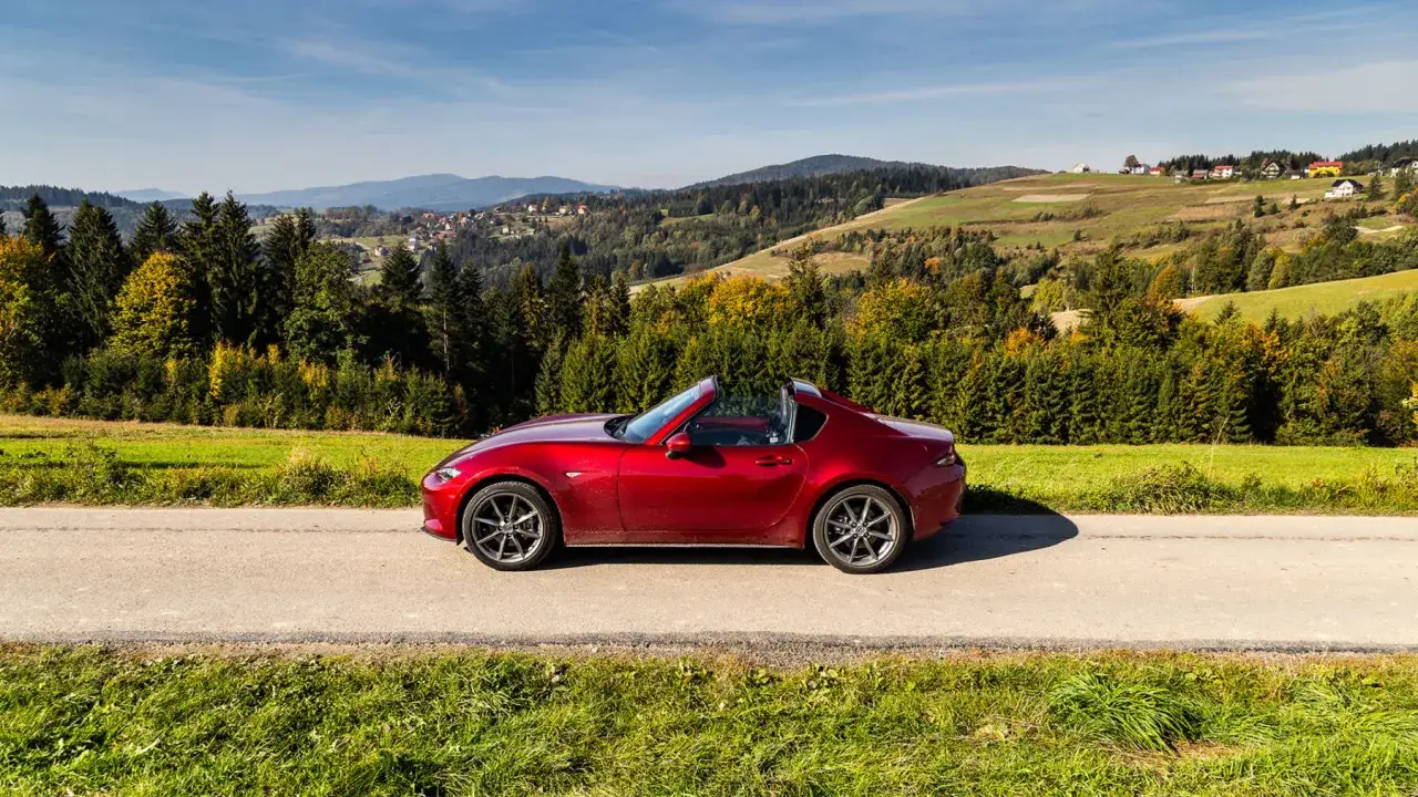 Czerwony roadster na drodze wśród beskidzkich wzgórz. Idealny do pokonywania zakrętów na Wielkiej Pętli Beskidzkiej.