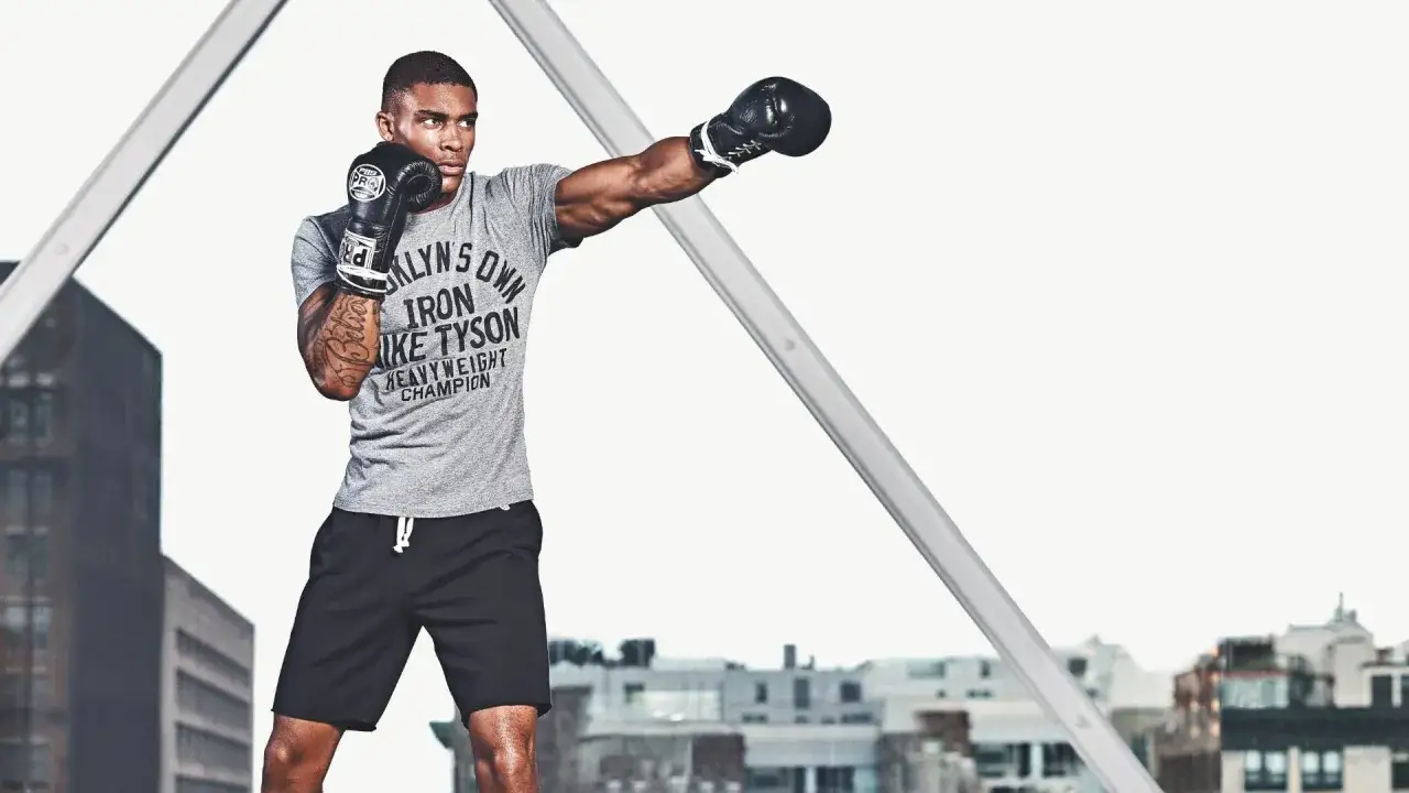 A boxer with boxing gloves is punching with weights, training like a heavyweight champion.