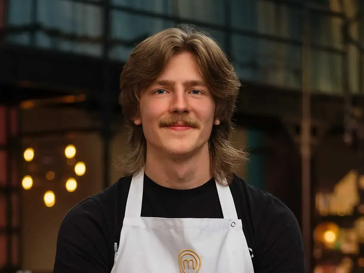 Jacob Jansson, en ung man med mustasch och långt hår, bär en vit kockförkläde.