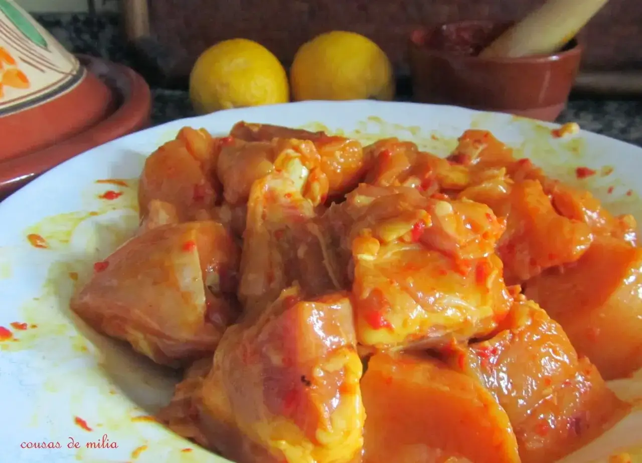 Trozos de pollo crudo marinados con especias anaranjadas, listos para preparar un delicioso taj&iacute;n de pollo.