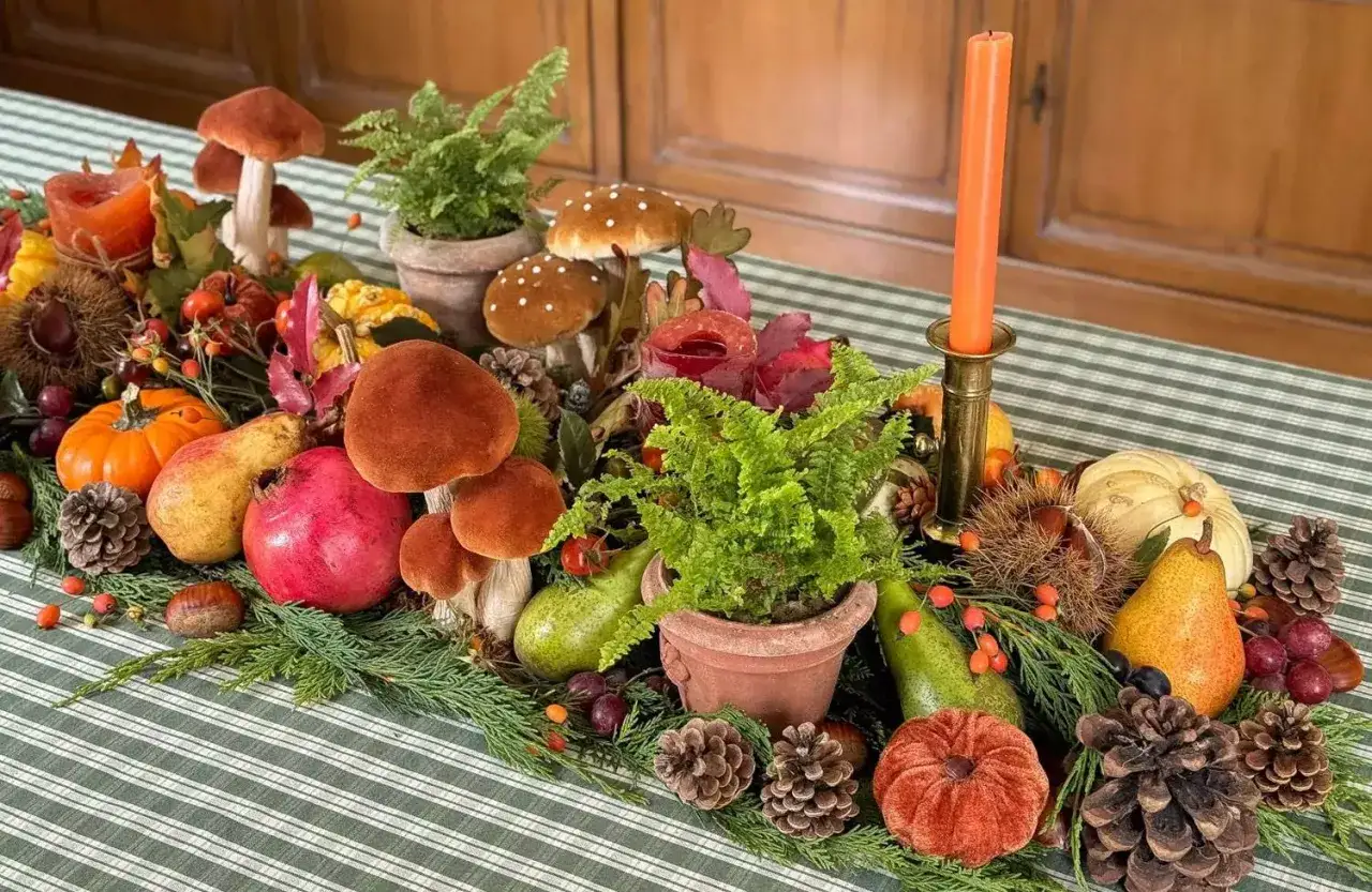 Décoration table automne facile : champignons, citrouilles, poires, grenades, fougères et pommes de pin sur une nappe à rayures vertes.