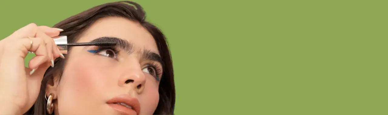 Una mujer aplica máscara de pestañas, un paso clave para aprender como maquillar ojos grandes y resaltar su belleza.