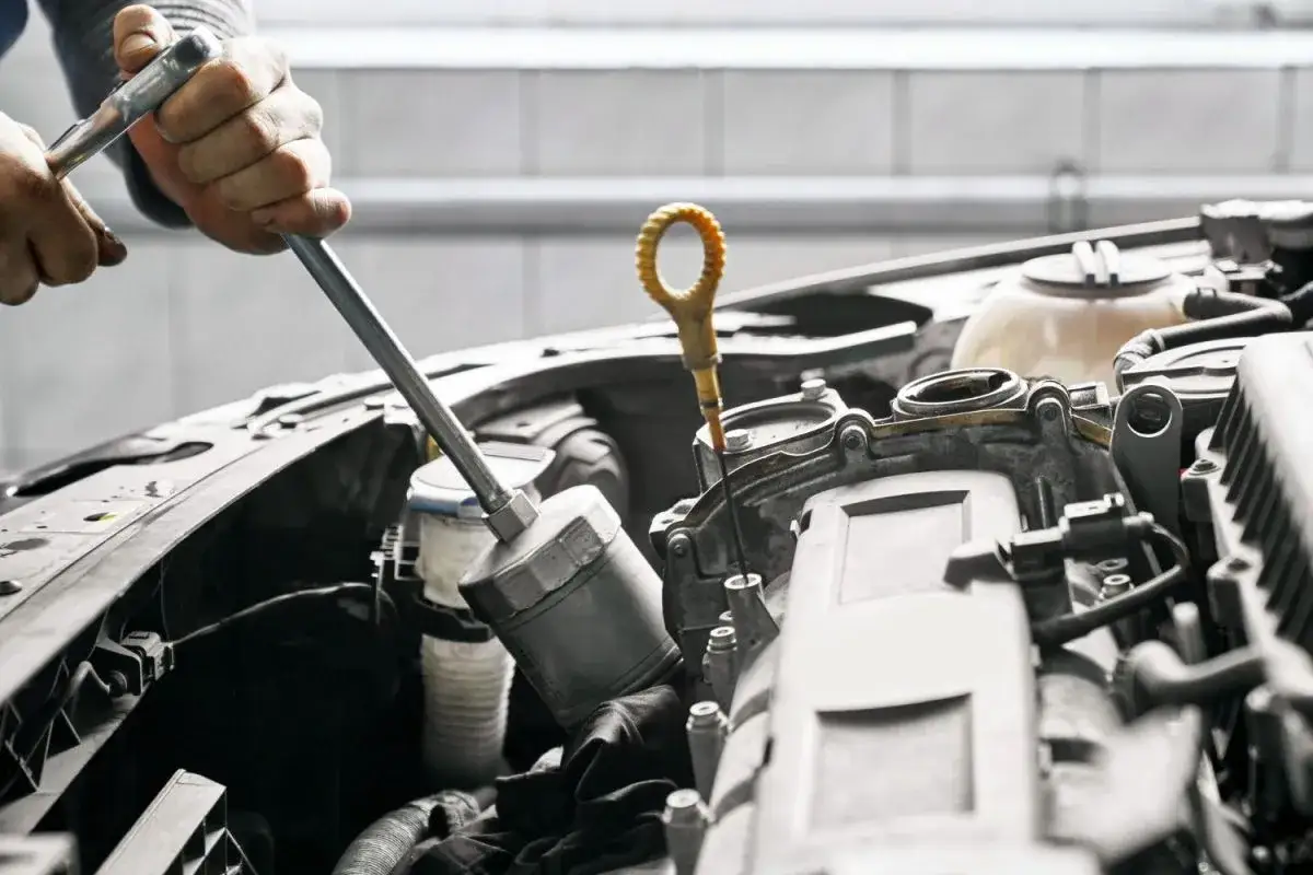 Mecánico trabajando en el motor de un coche, quizás intentando averiguar como arrancar un coche con los calentadores estropeados.