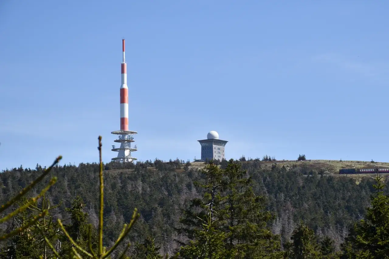 Wieże i budynki na szczycie Brocken w g&oacute;rach Harz w Niemczech. W oddali widać pociąg.