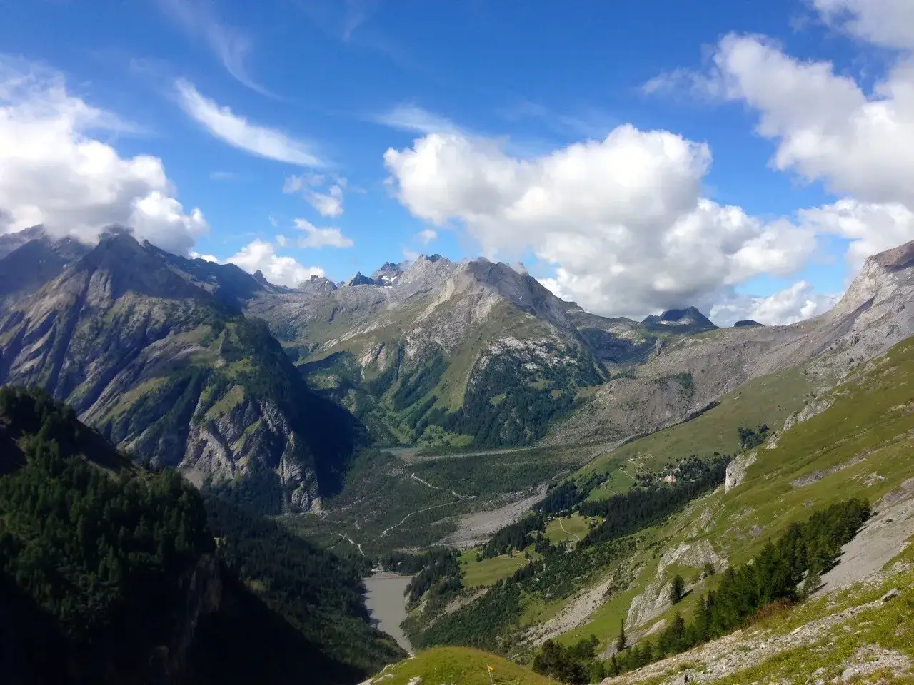 Majest&auml;tische Berglandschaft im Rahmen der Tour des Muverans. Gr&uuml;ne T&auml;ler, schroffe Gipfel und ein blauer Himmel mit Wolken.