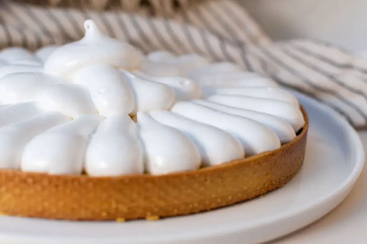 Tarte garnie de meringue suisse, d'une croûte dorée et d'une garniture crémeuse.