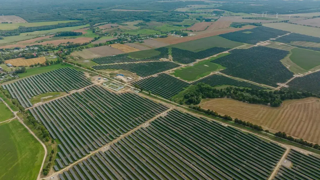 Ogromne połacie paneli słonecznych tworzą największą farmę fotowoltaiczną w Polsce, otoczoną polami i lasami.