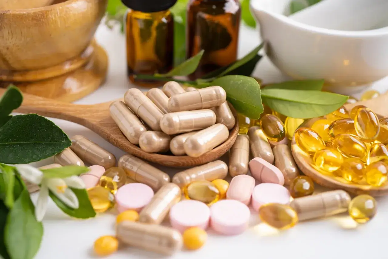 Kapseln und Pillen, darunter ein Vitamin B Komplex und Zink zusammen einnehmen, liegen neben Kräutern und Öltropfen.