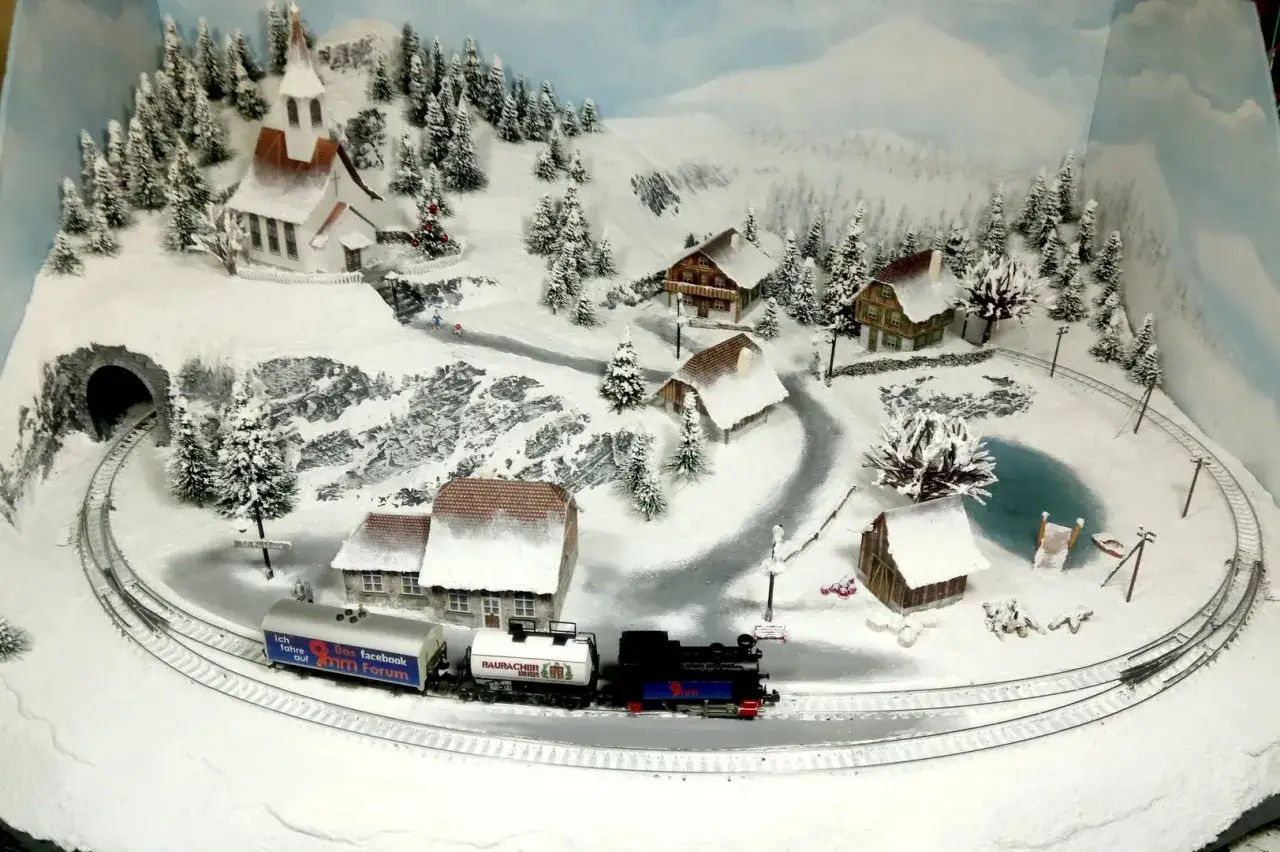 Winterwunderland im Modellbau: Ein Zug fährt durch verschneite Dörfer. Hier wurde Modellbau Schnee selber gemacht, um eine zauberhafte Winterlandschaft zu erschaffen.