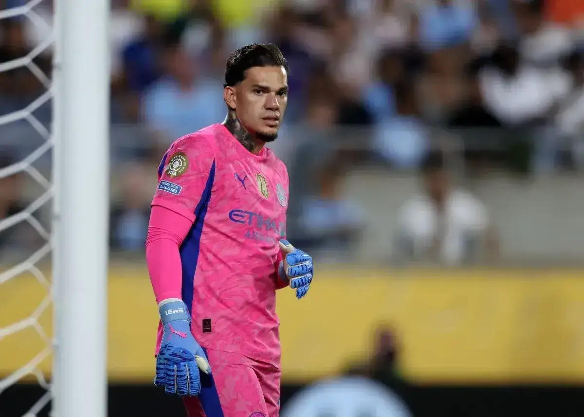 Bramkarz Manchester City w różowym stroju, gotowy do obrony.