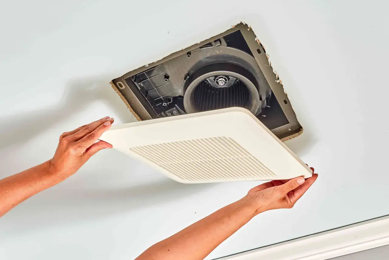 Manos colocando la cubierta de un extractor de ba&ntilde;o.