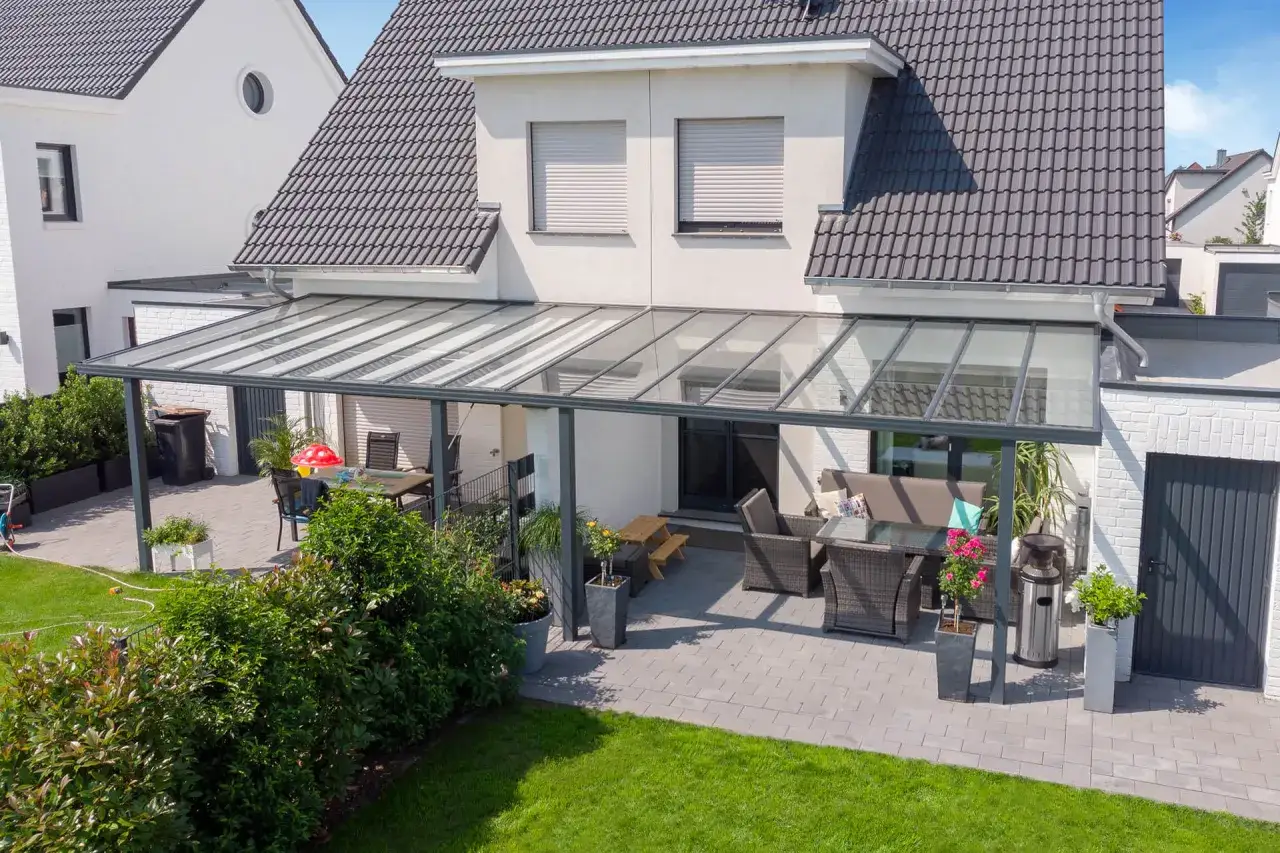 Terrasse mit Glas&uuml;berdachung und Gartenm&ouml;beln. Hier stellt sich die Frage: Kann der Nachbar die Zustimmung zur Grenzbebauung verweigern?