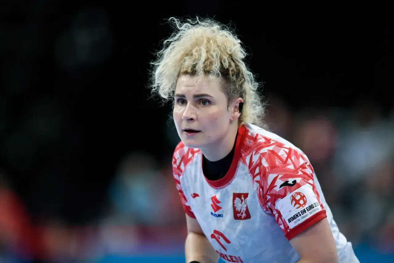 Sylwia Matuszczyk, zawodniczka w białej koszulce z czerwonymi wzorami, skupiona na boisku.