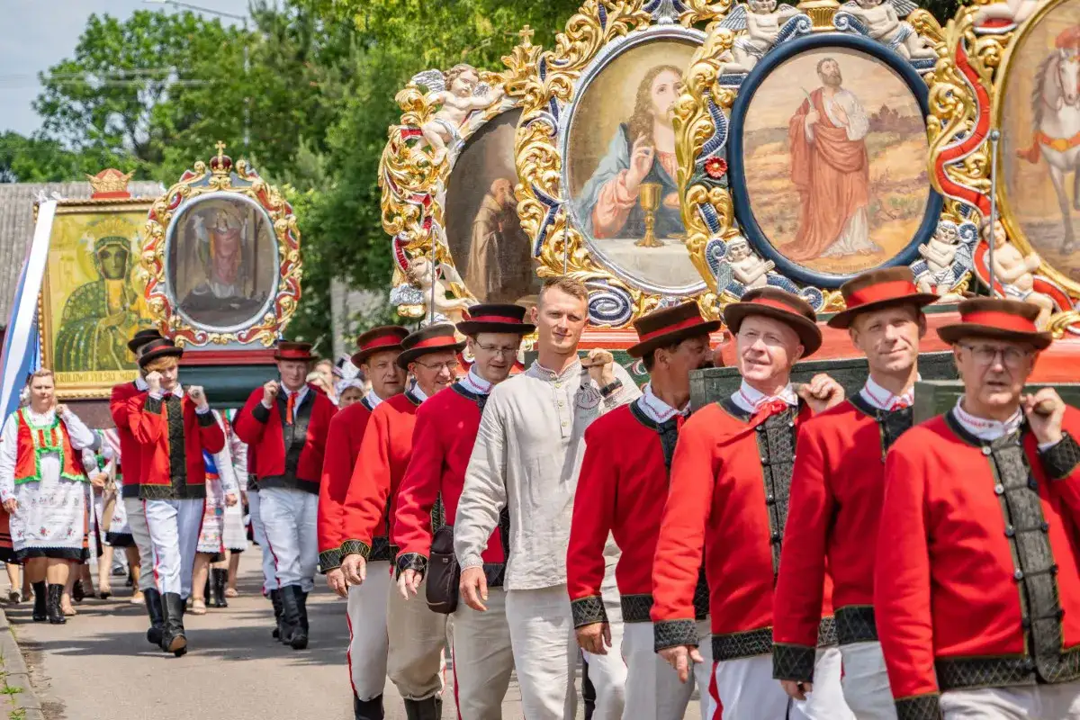 Procesja Bożego Ciała, z obrazami świętych i ludźmi w strojach regionalnych. Tradycja wyjaśnia, dlaczego Boże Ciało jest w czwartek.