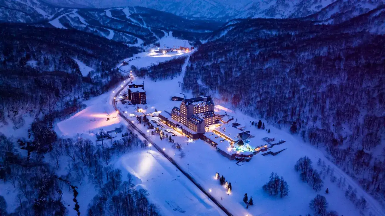 Winter in Japan: Ein beleuchtetes Resort in verschneiter Berglandschaft bei Nacht.