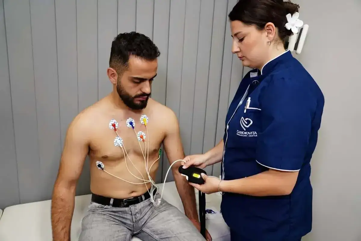 Mężczyzna z elektrodami na klatce piersiowej podczas badania holter ekg, pielęgniarka podłącza urządzenie.